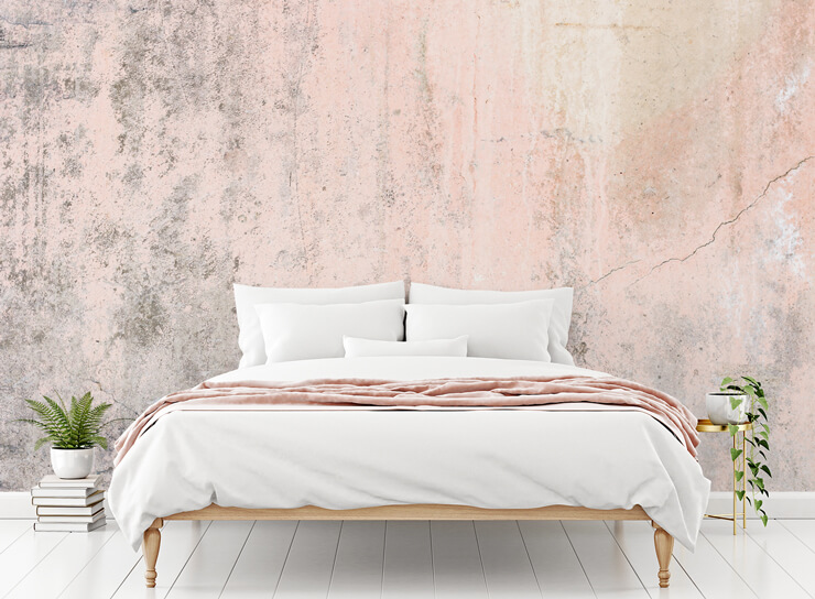 grey and pink cracked concrete wallpaper in bedroom with bed with white and pink bedding and green plant