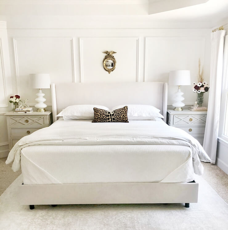 white panelled wall bedroom with white bed and bedside cabinets