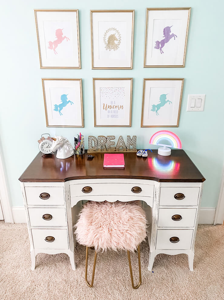 unicorn white desk with framed unicorn prints on wall and pink furry stool