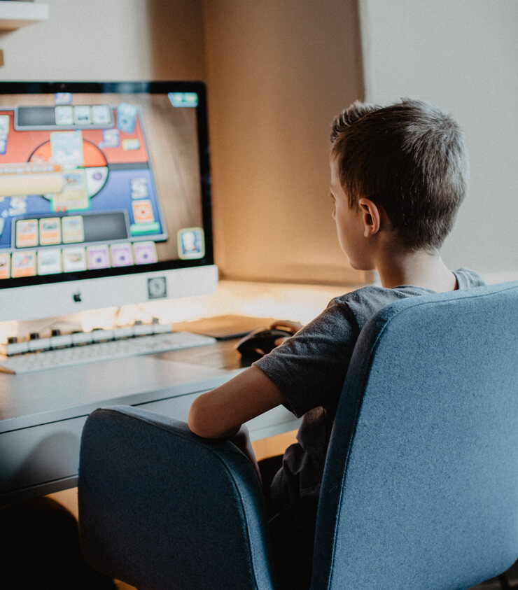 boy sat on comfy grey chair learning on the computer