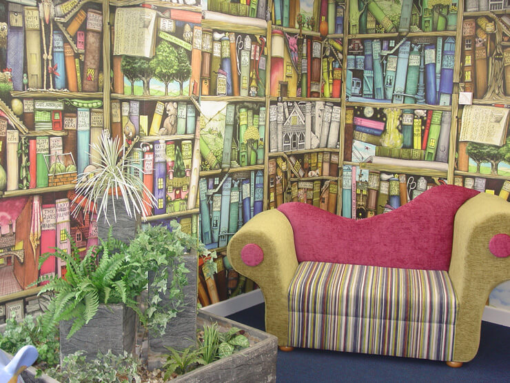 multicoloured illustrated bookshelf wallpaper in reading corner