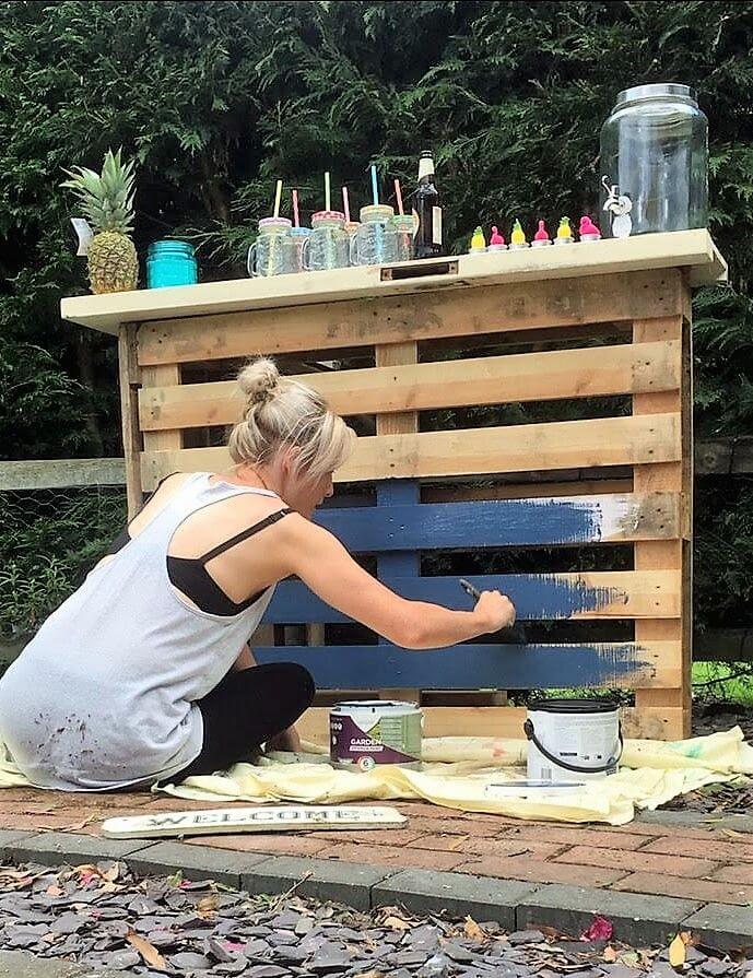 blonde woman painting pallet bar navy blue