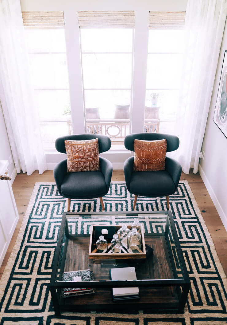 dark green and white patterned rug in cool lounge with two grey chairs