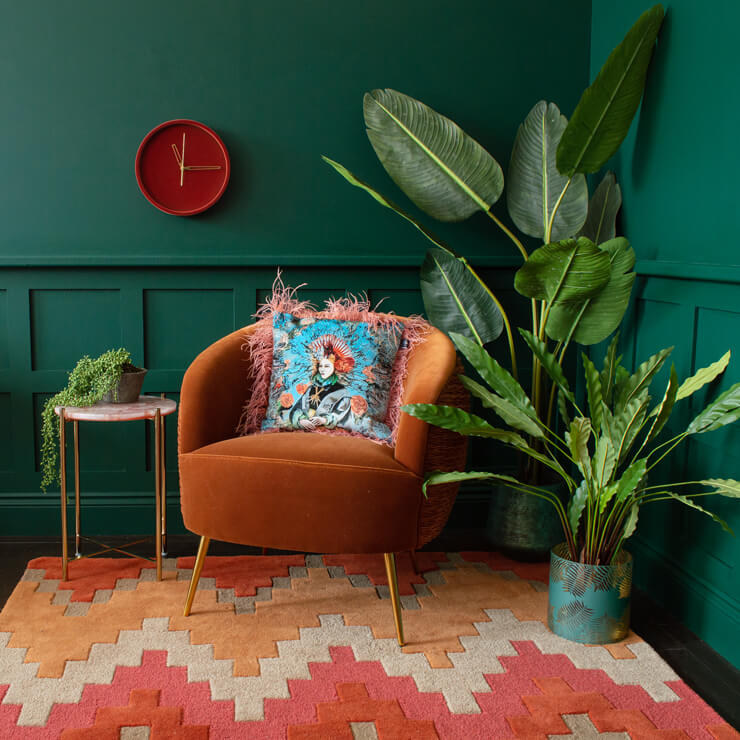 patterned orange rug with dark green panelled walls and orange chair
