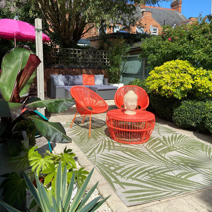 green and off-white palm leaf rug in garden