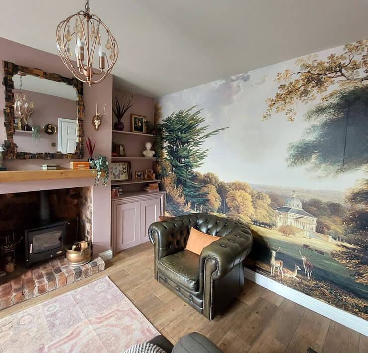 stately home painting wallpaper in cosy living room with dusty pink walls and green armchair