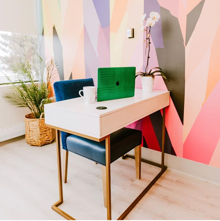 multicoloured patterned wallpaper with blue office chair and white desk