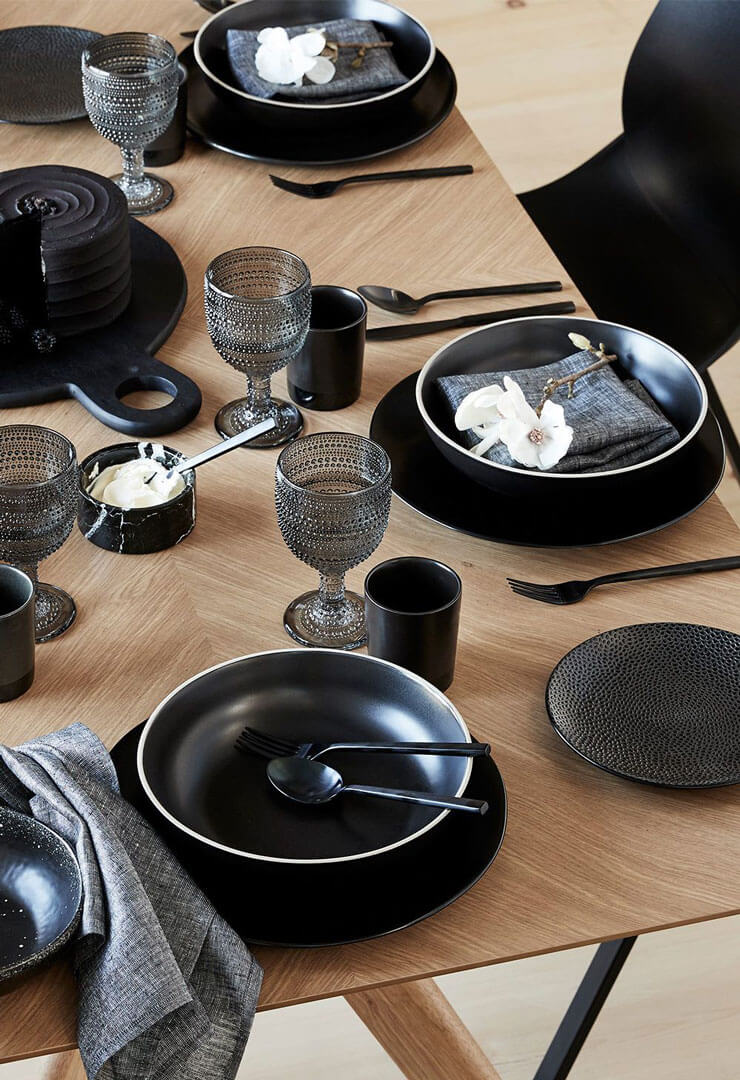 Wooden dining table with black plates and knives and forks