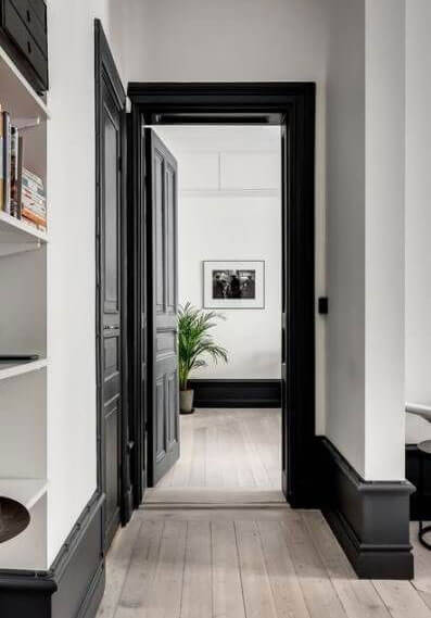 White walls in a hallway with black skirting boards and doors