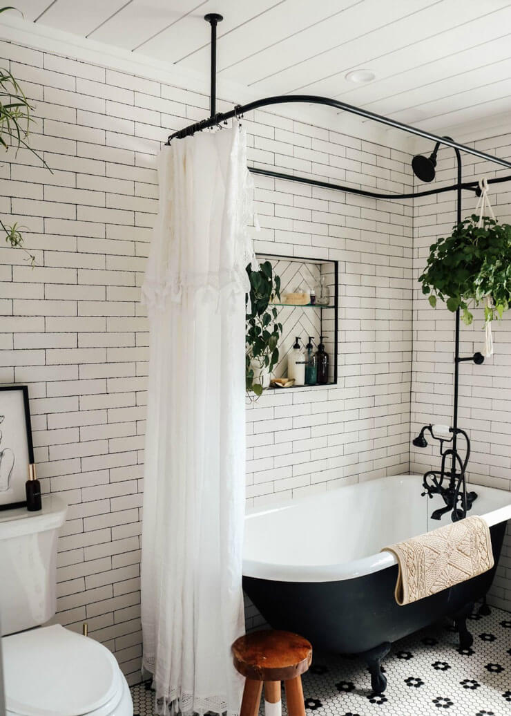 Black and white bathroom with a black bathtub and curtain rail