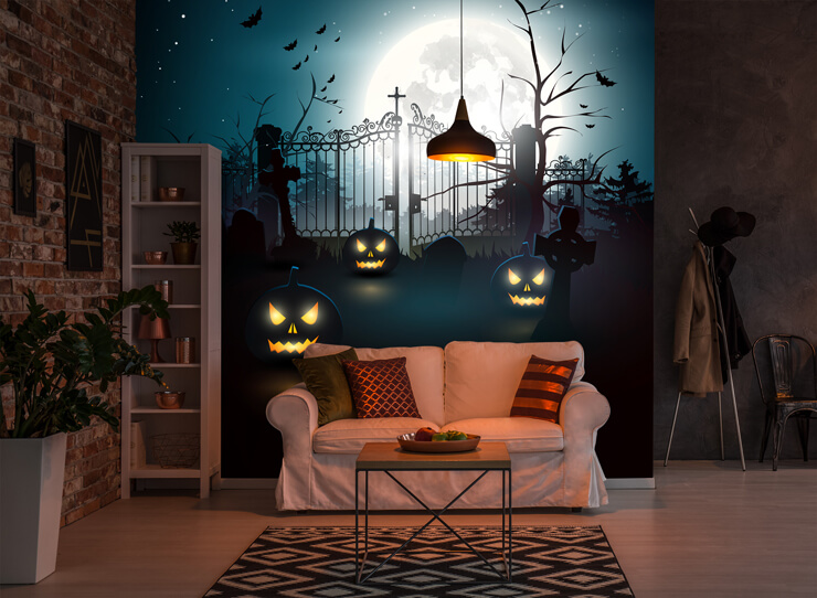 Dark living room decorated with Halloween items including a pumpkin graveyard wall mural