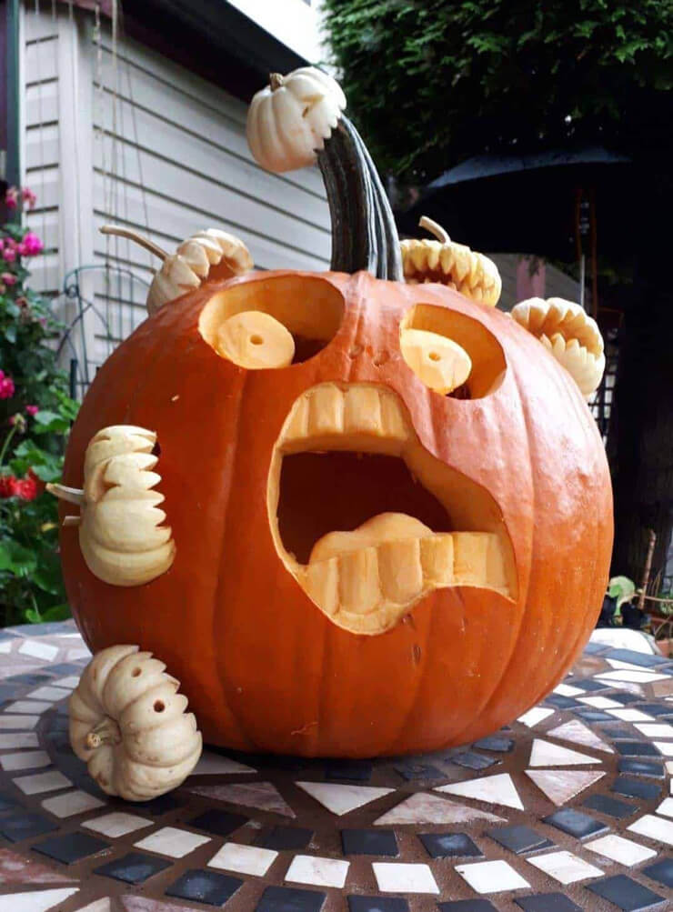 Pumpkin carving ideas for a large orange pumpkin being eaten by smaller white pumpkins