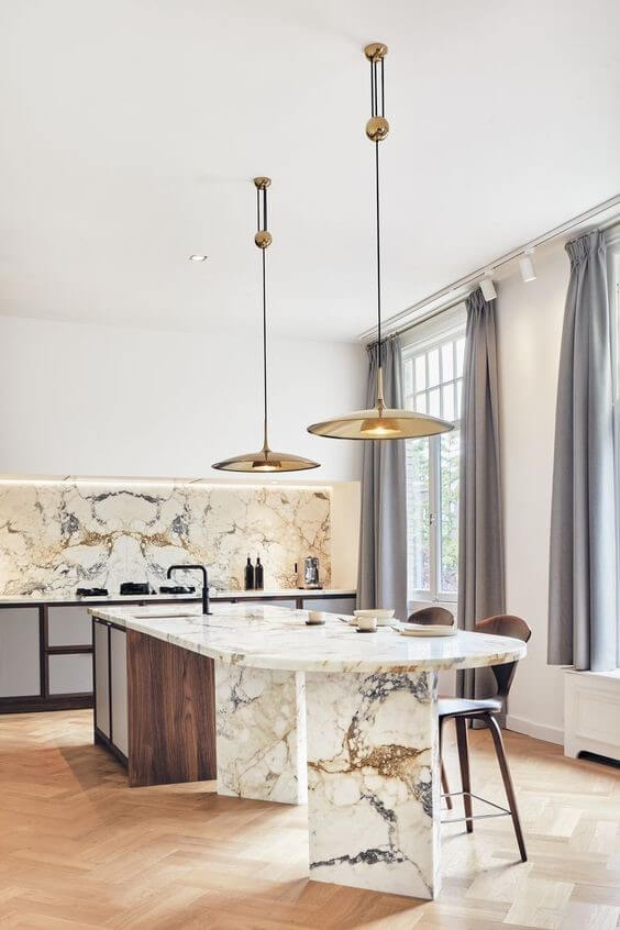 Beige marble worktops in a kitchen with curved worktop and cupboards