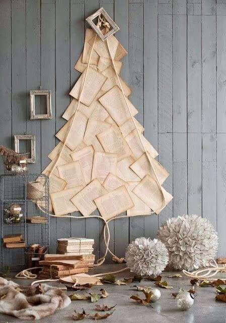 Christmas tree made from old book pages on a grey wood panelled wall 
