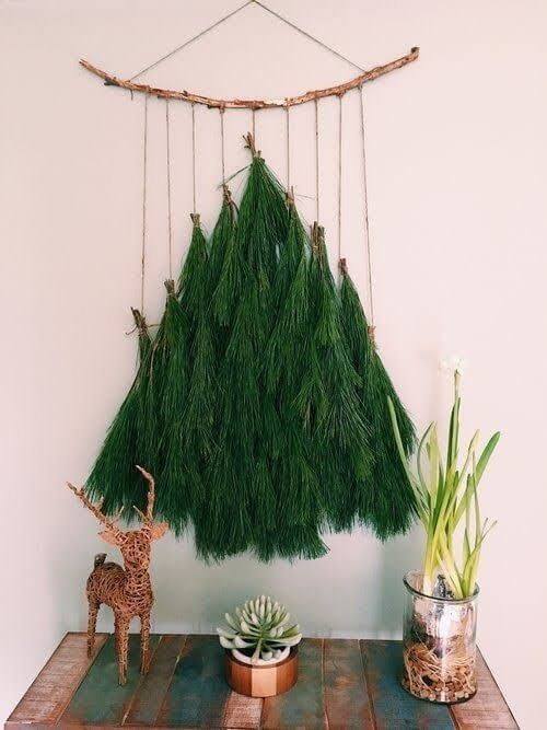 Green leaves hung on a white wall to mimic a Christmas tree