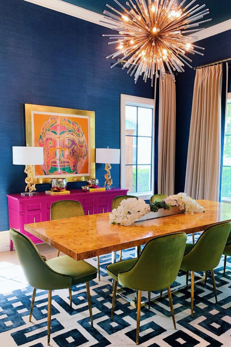 Bright dining room with blue walls, a pink unit and a wooden table with green chairs