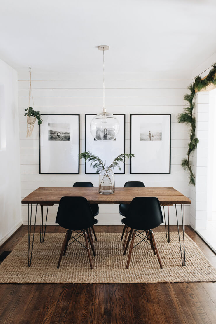 Neutral dining room inspiration with white walls, a wooden table and black chairs on a wicker rug