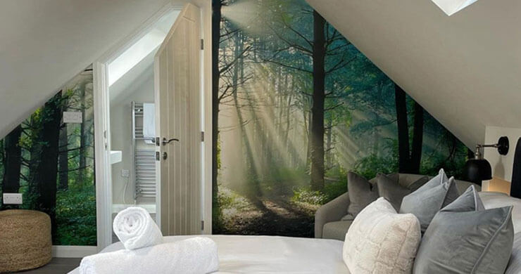 Customer photo of a hotel room with white bedsheets and a realistic woodland wallpaper