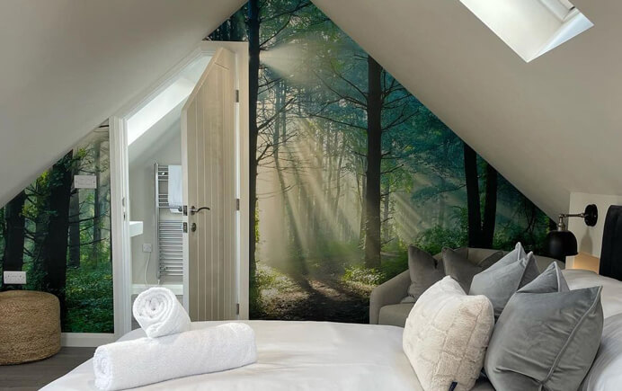 Customer photo of a hotel room with white bedsheets and a realistic woodland wallpaper