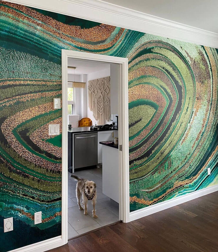 Large wall with a green and gold marble effect wallpaper with a dark wooden floor