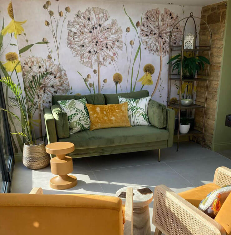 Yellow and green garden room with floral wallpaper, mustard yellow chairs and a green sofa