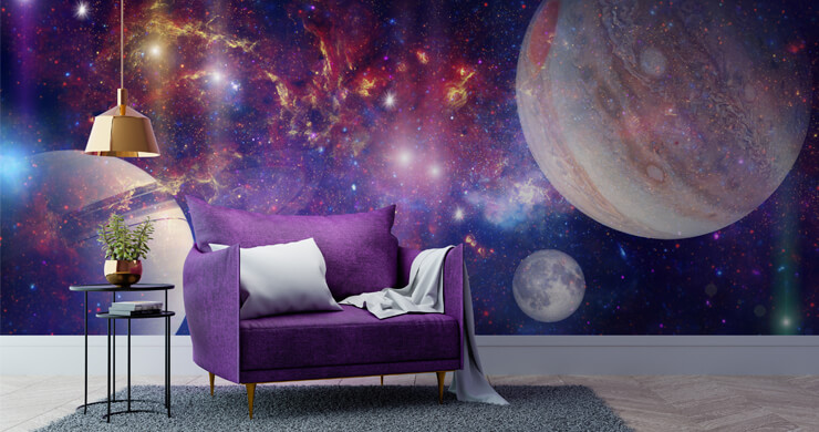 Space wallpaper with purple and blue swirls and stars with large planets in a living room with a purple chair and white wood flooring