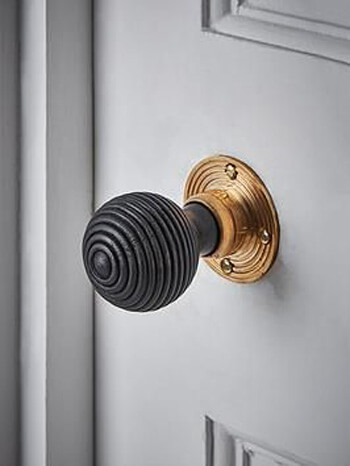 Black and brass door handle on a white door