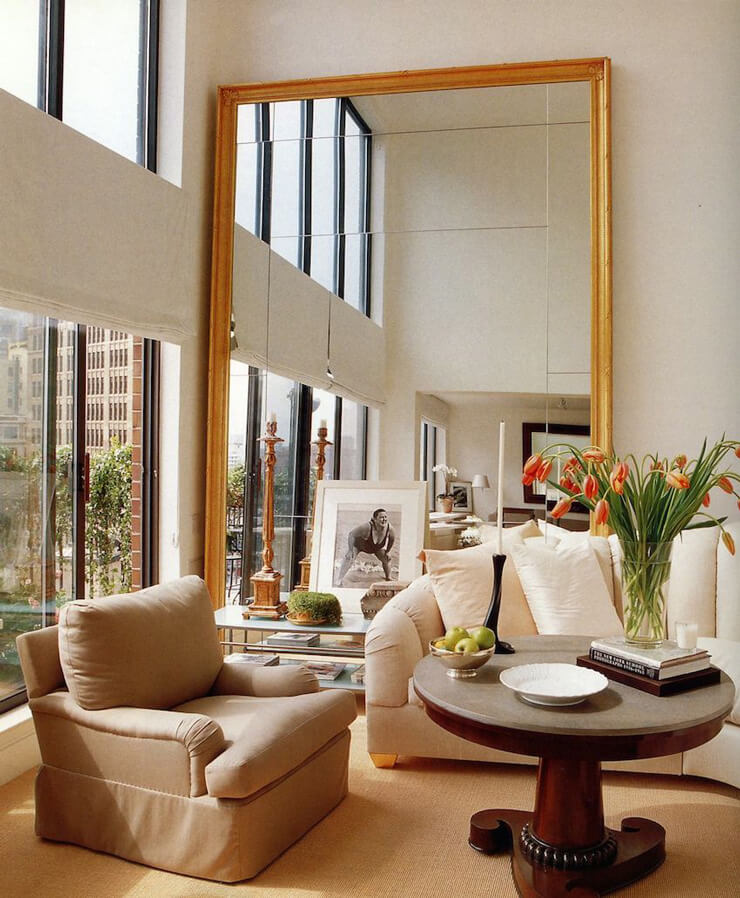 Beige and cream living room with a beige chair and large wood framed mirror