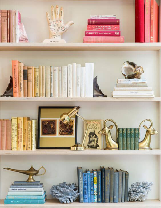 White bookshelves with groups of books styled in colour co-ordination