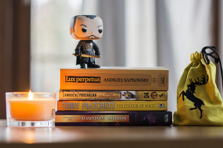 Stack of fantasy books with a figurine and a candle Stack of fantasy books with a figurine and a candle