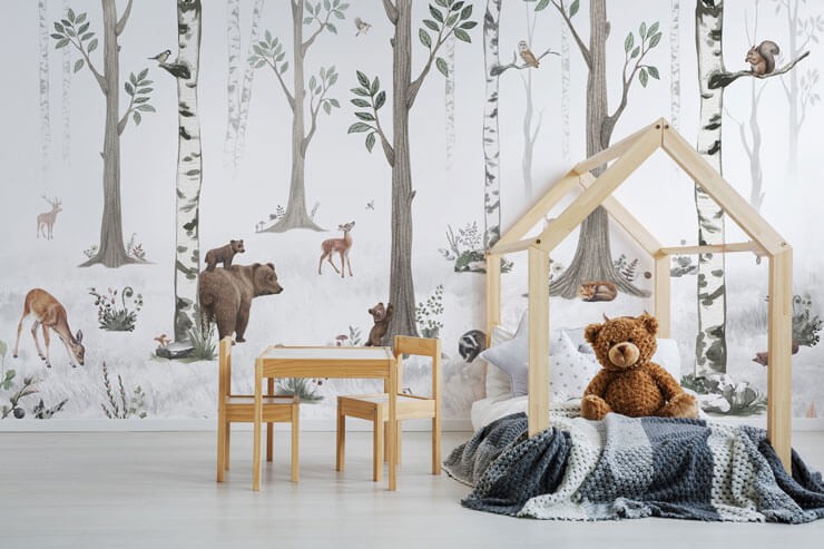 Kid's bedroom with a white woodland wallpaper with illustrated animals with a pine bed frame with grey bed sheets