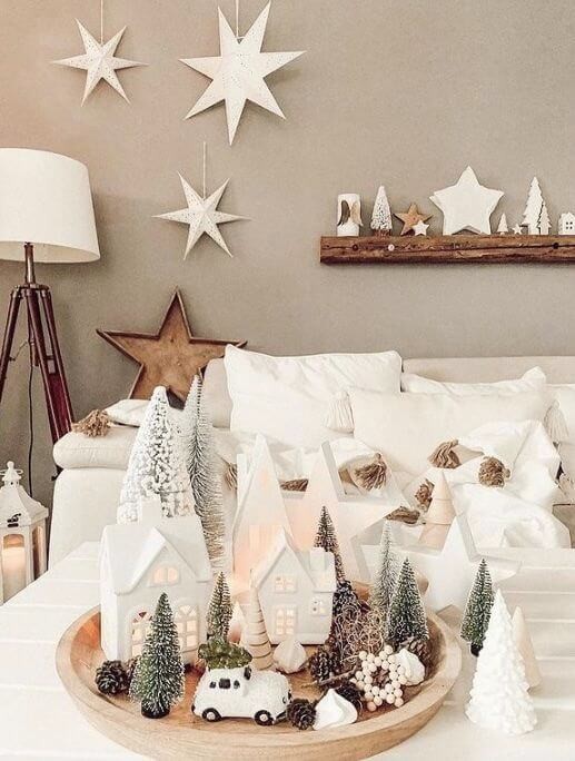 Neutral Scandinavian Christmas Decorations in form of ceramic houses and green faux trees in a white living room