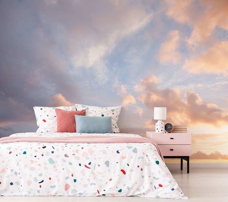 blue sky and pink sunset clouds wall mural in bedroom with terrazzo pastel duvet covers