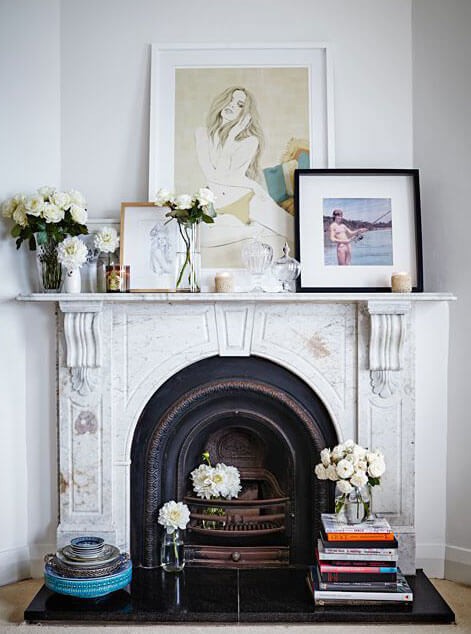 neutral mantelpiece with layered ornaments and frames on top