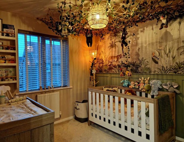 Nursery with wooden furniture a tiger jungle wallpaper and rope and leaves on the ceiling