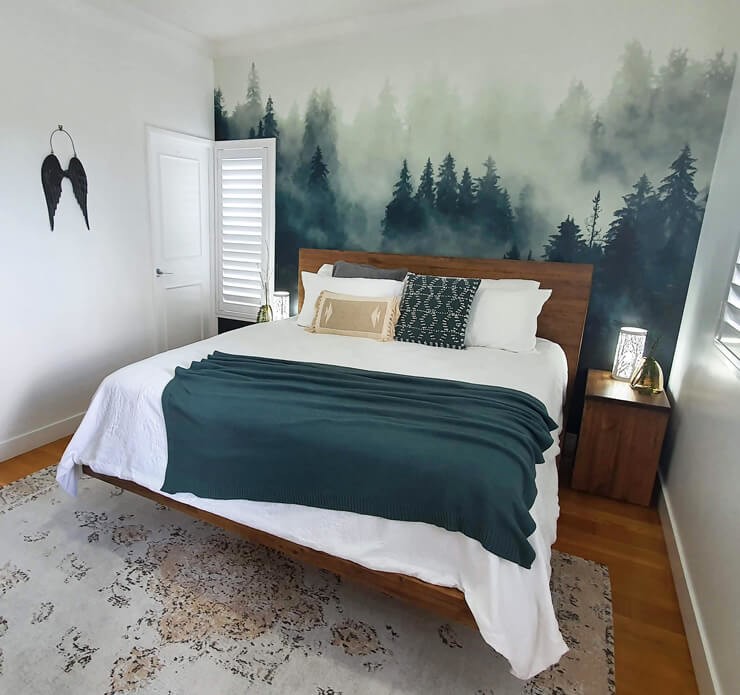 dark green misty forest wallpaper in bedroom with bed with white and green bedding