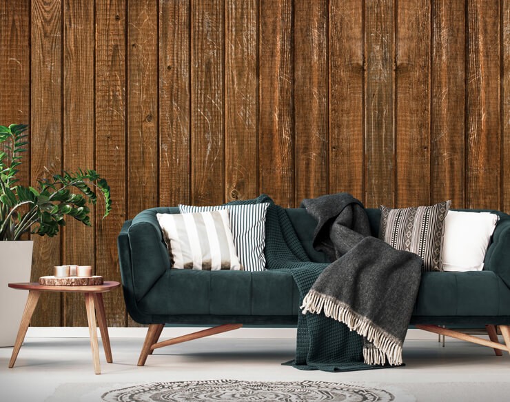 Wood panelled wall mural behind a dark green sofa with white cushions 