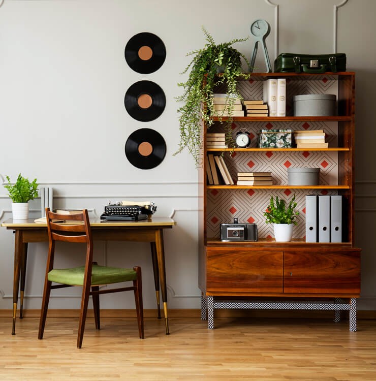 how to style your bookshelves with a mixture of portrait and landscape books and ornaments with plant pots in a dark wooden cabinet