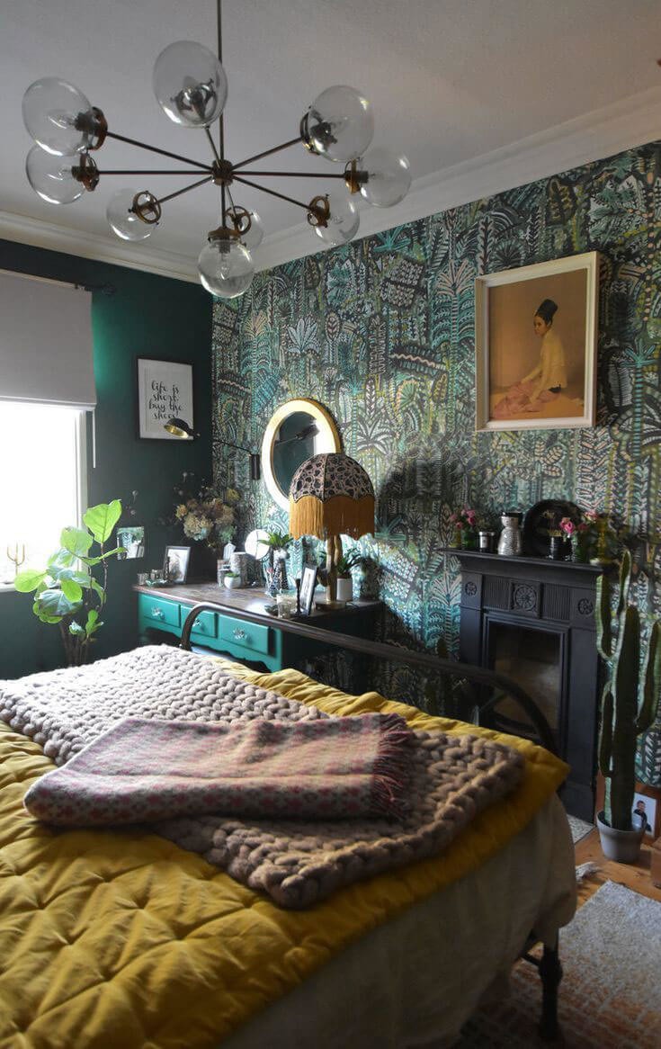Dark green and teal bedroom with a black fireplace and mustard bedsheets