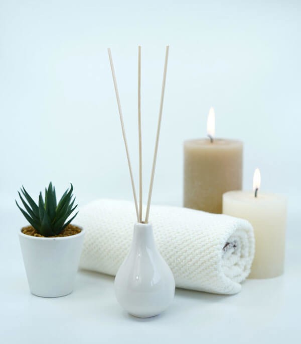 white candles, rolled towel and reed diffusers