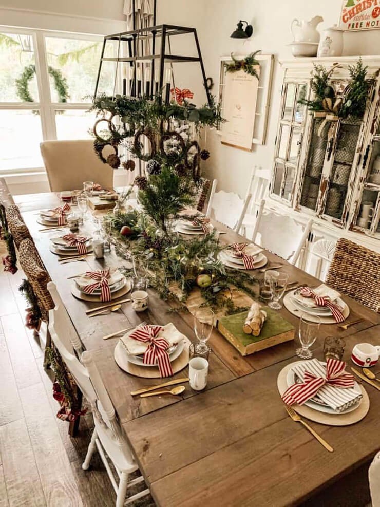 Large dark wooden table in a farmhouse with white plates and green garland