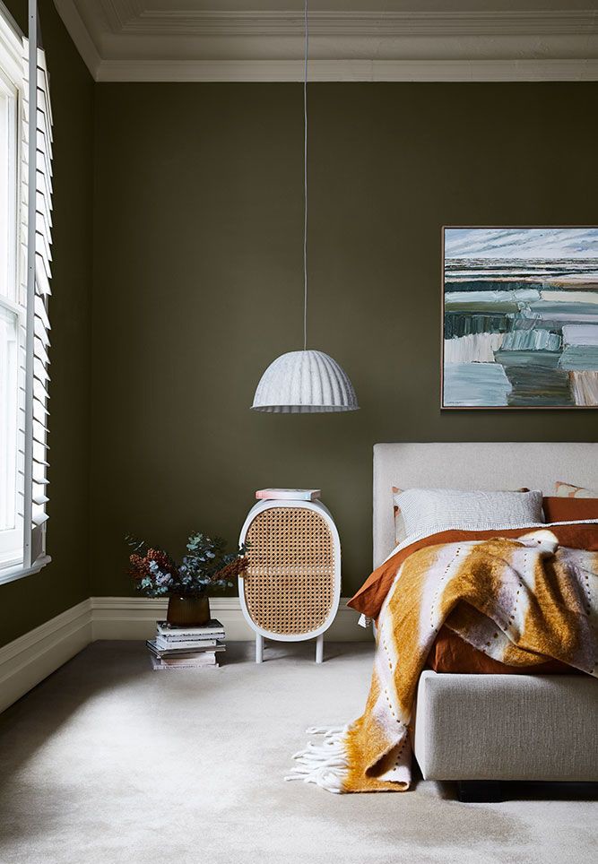 mossy green painted walls in bedroom with tumeric-orange room accessories