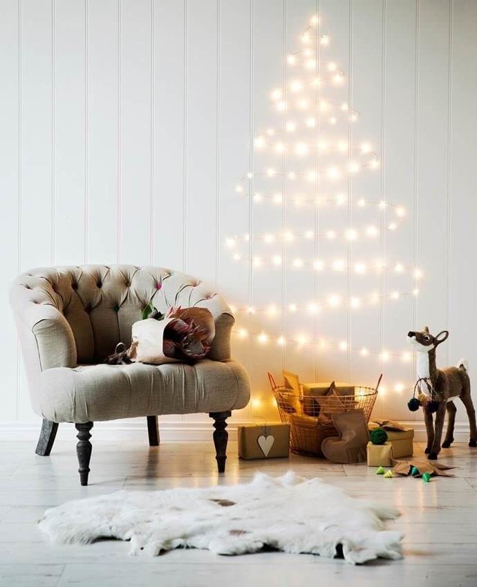 Christmas tree made from lights on a white wooden wall with a grey chair
