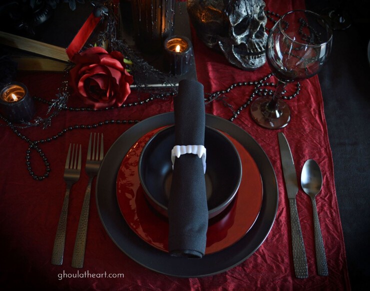 Red and black tableware with a black napkin held by whitevampire teeth