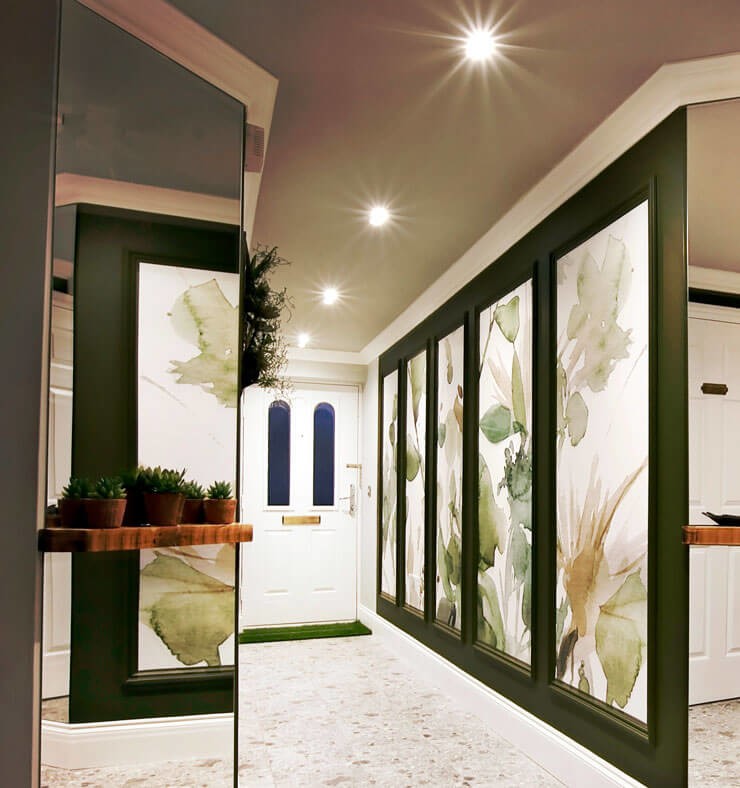 Long hallway with a framed floral green wall mural with dark green walls and a cream terrazzo floor
