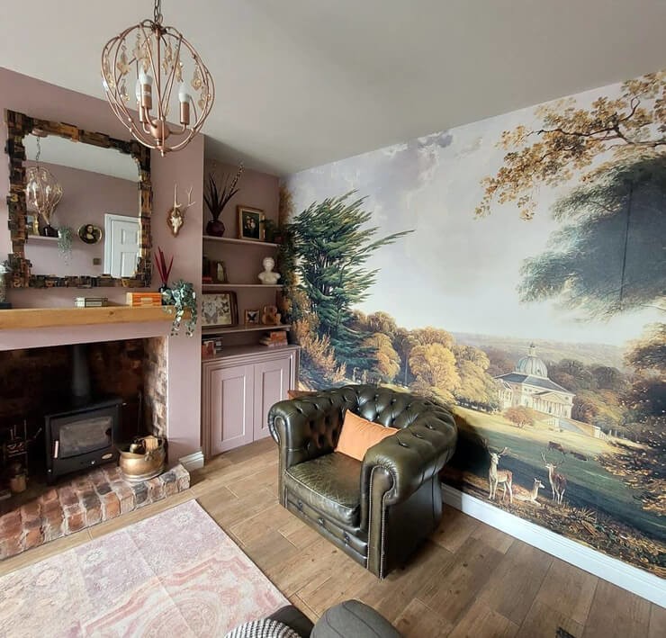 stately home painting wallpaper in cozy living room with dusty pink walls and green armchair