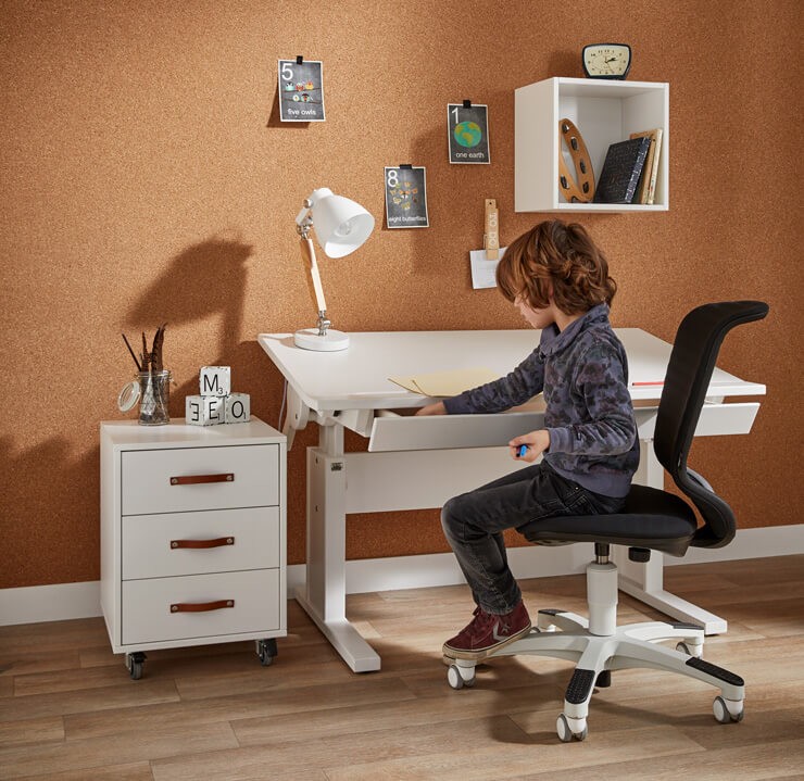 child sized chair and desk with long haired boy enjoying home schooling