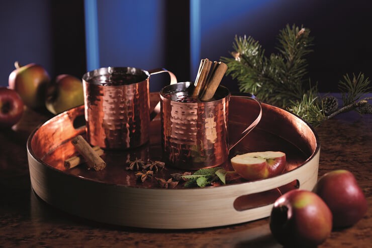 copper dented mugs on a tray with mulled cider