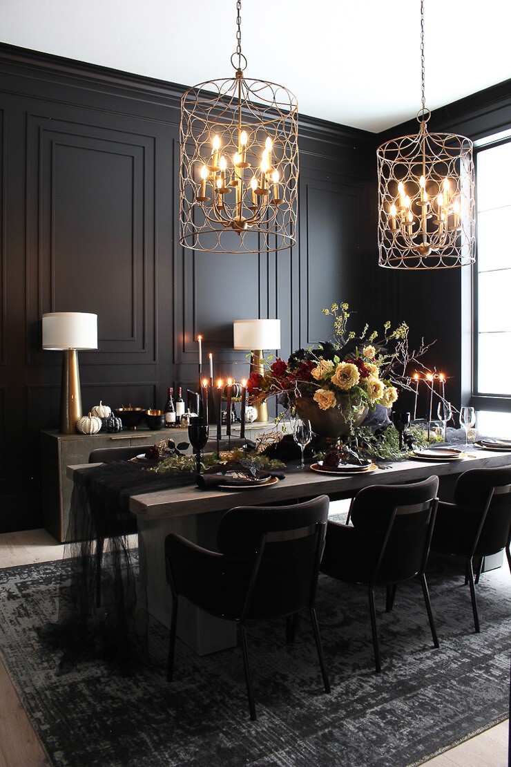 Dark dining room with black panel walls and a black dining table with a dark grey rug