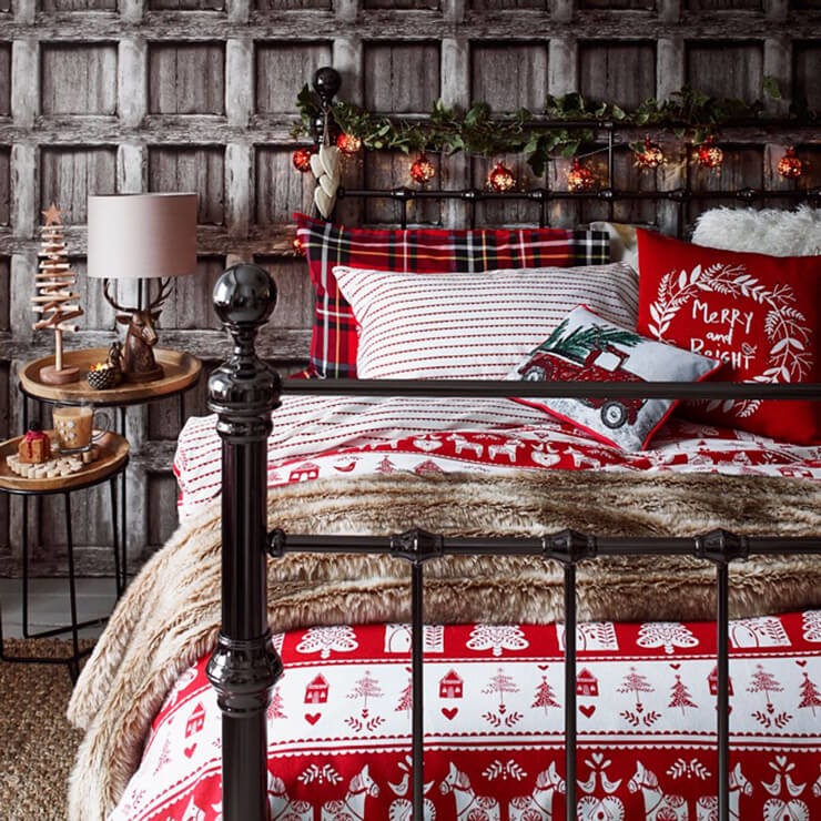 White, grey and red bedsheets in a cabin style bedroom with wood panel walls and a black bed frame